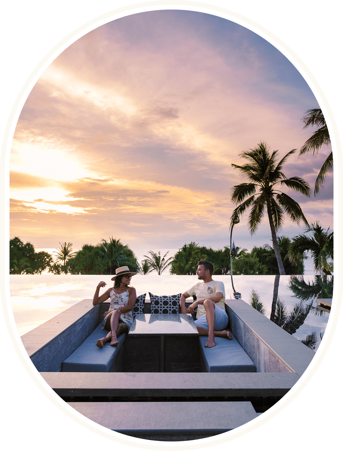 Couple relaxing by pool with palm trees.
